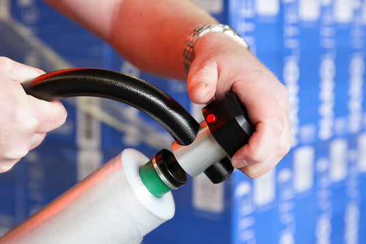 A close up image of a person screwing the end onto the bolt dispenser after putting a fresh roll of wrap on to it. 